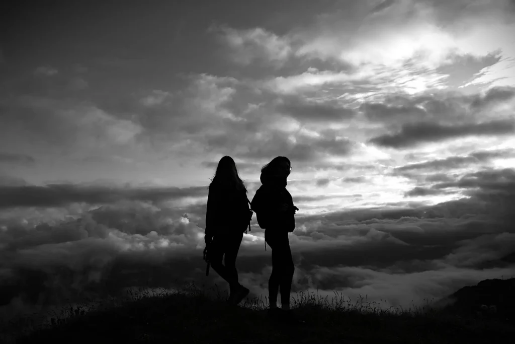 2 personnes au sommet d'un mont avec une mer de nuage en arrière plan