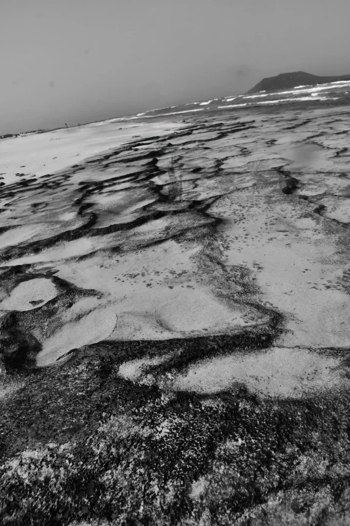 le sol apparent après que l'océan se soit retiré. Il laisse admirer quelques minis baignoires naturelles entourées de roches et de sable. Photo en Noir et blanc