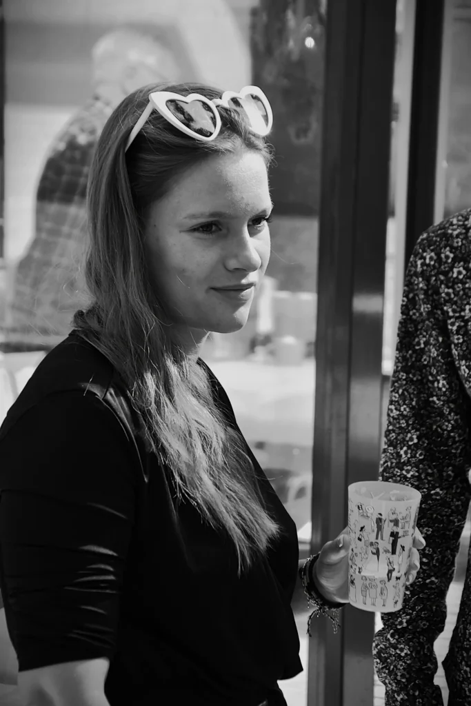 Portrait d'une jeune femme lunettes de soleil en forme de coeur sur la tête et un verre à la main