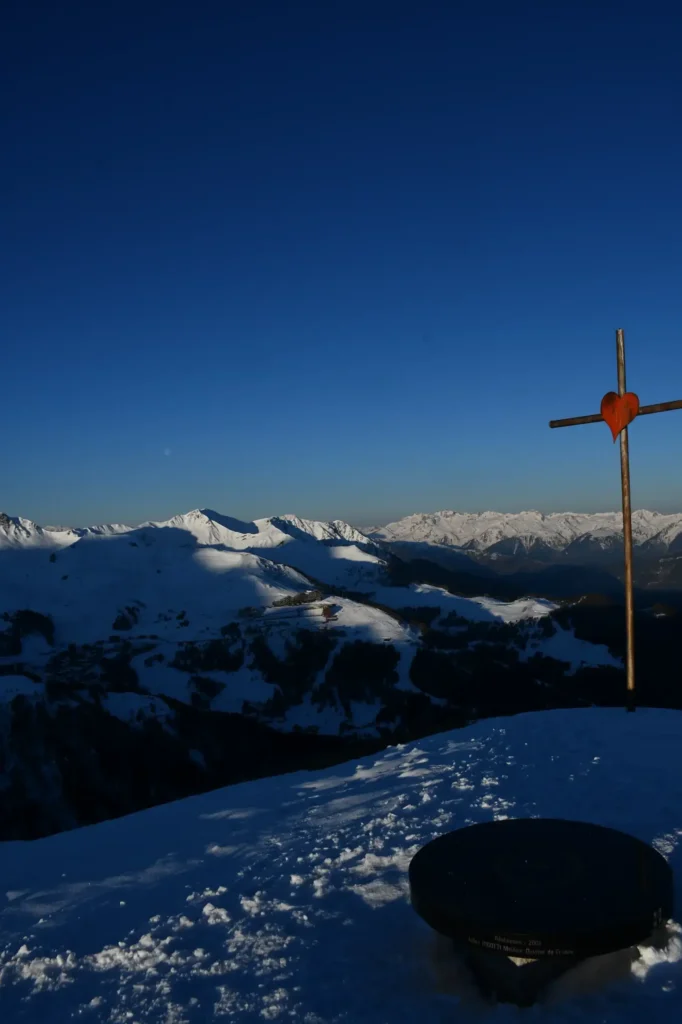 Au lever du soleil l'hiver au sommet d'une montagne avec une croix surmontée d'un coeur au centre