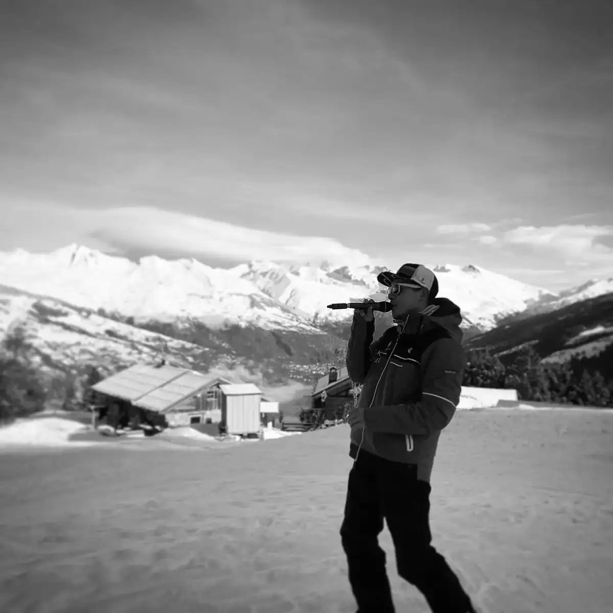 Alexis au micro sur un bord de piste de ski avec une casquette, un manteau d'hiver et son micro porté à la bouche