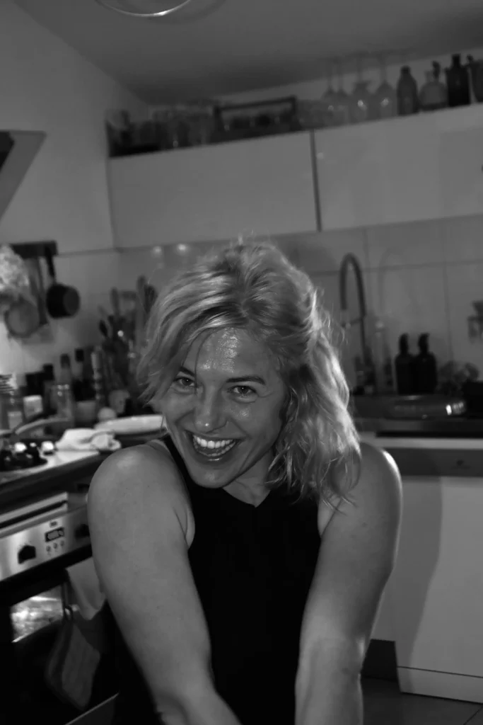 Femme souriante au premier plan avec une cuisine en arrière plan