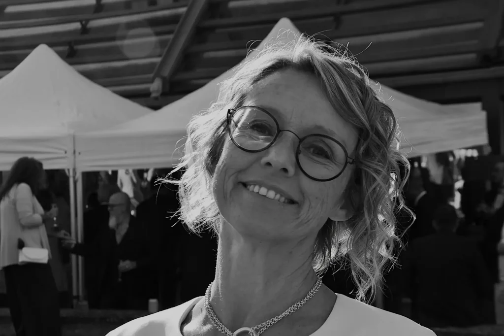 Personne souriante lors d'un mariage avec des tonnelles et du monde en arrière plan