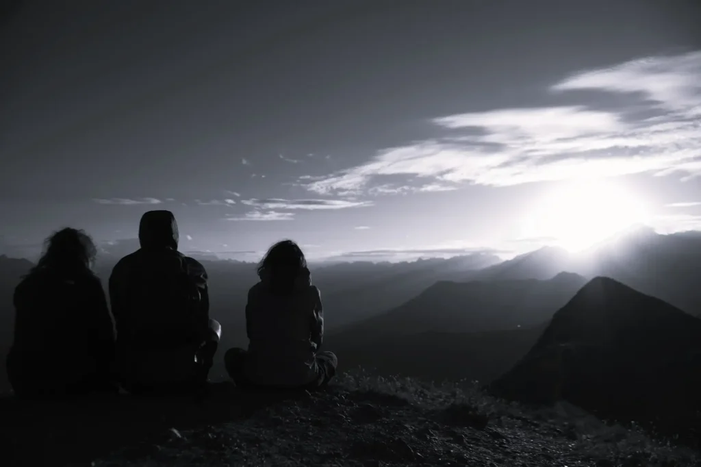 trois personnes au sommet d'une montagne lors d'un lever de soleil