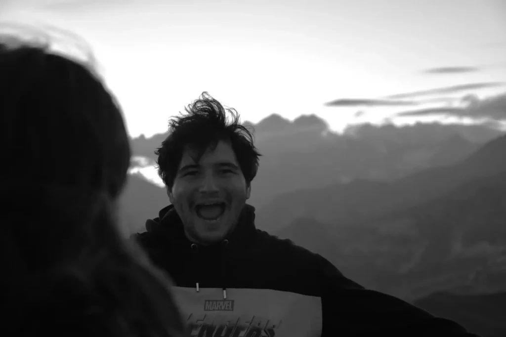 Jeune homme souriant au sommet d'une montagne lors d'un lever de soleil