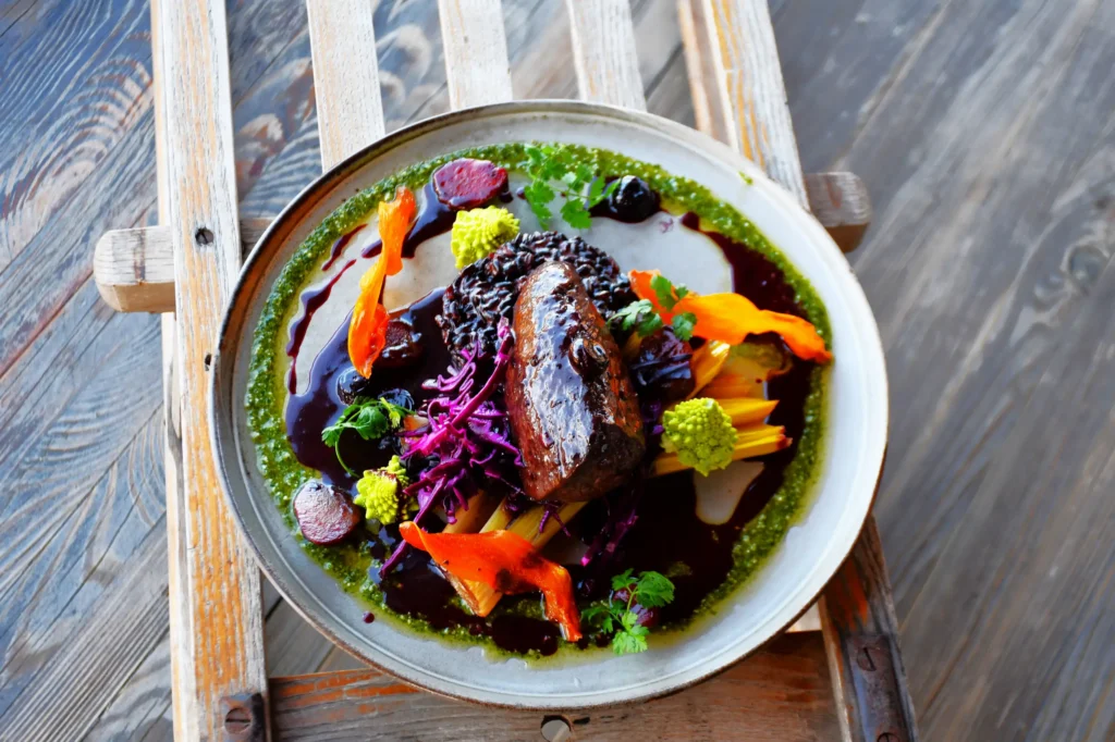 plat de restaurant, du cerf agrémenté de sa réduction et accompagné de légumes