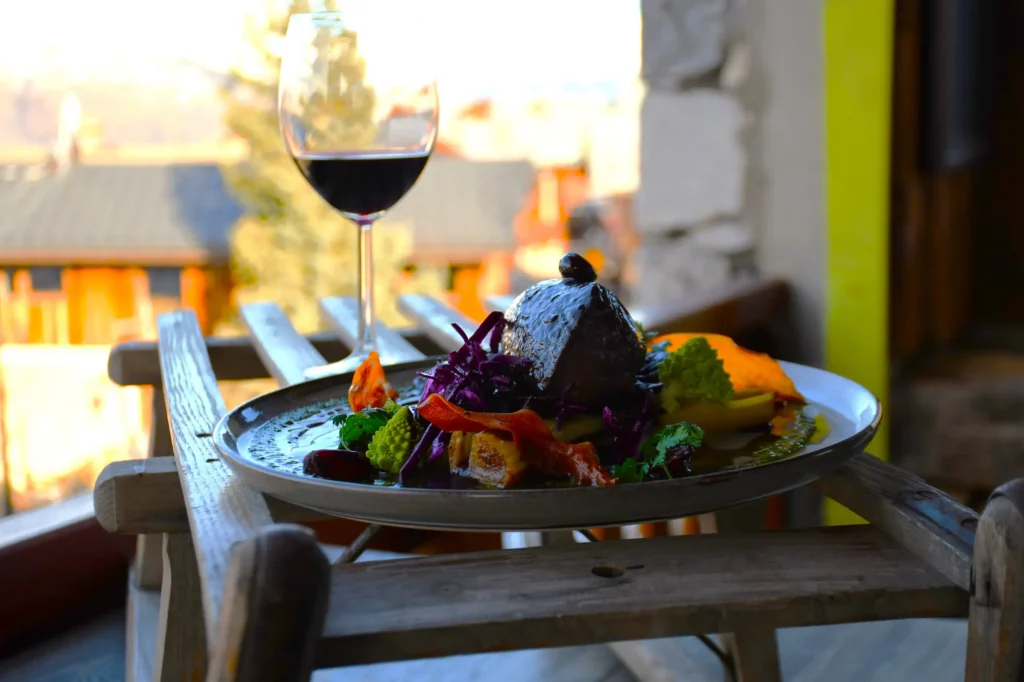plat de restaurant, du cerf agrémenté de sa réduction et accompagné de légumes et de son verre de vin rouge