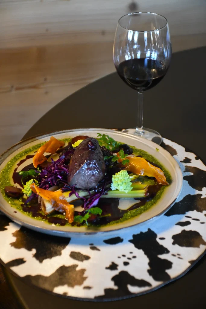 plat de restaurant, du cerf agrémenté de sa réduction et accompagné de légumes et de son verre de vin rouge