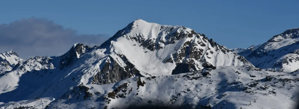 montagne enneigée avec du ciel bleu et un nuage gris sur la gauhe