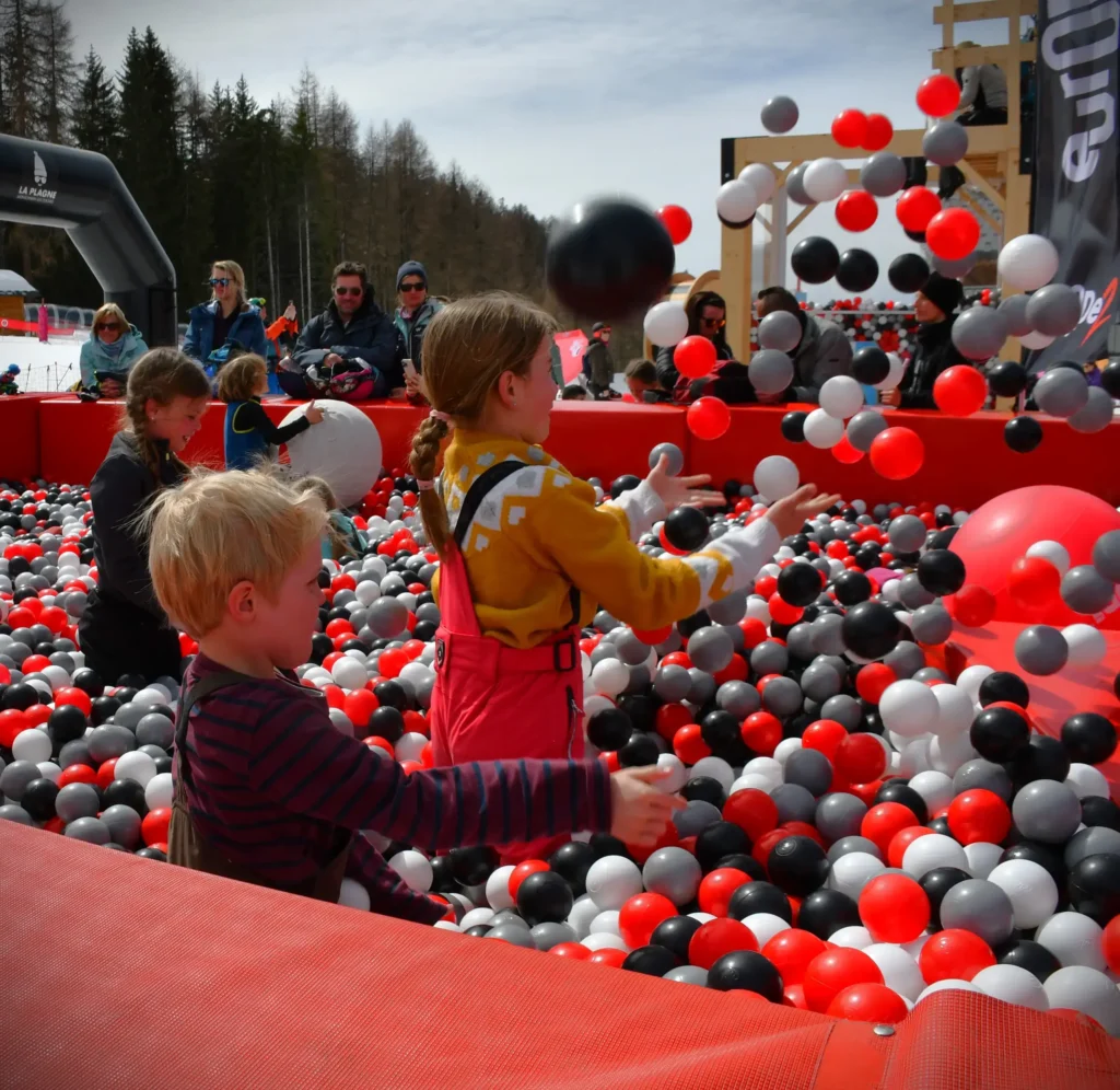 jeunes dans une piscine à balles au premier plan avec des adultes au second plan